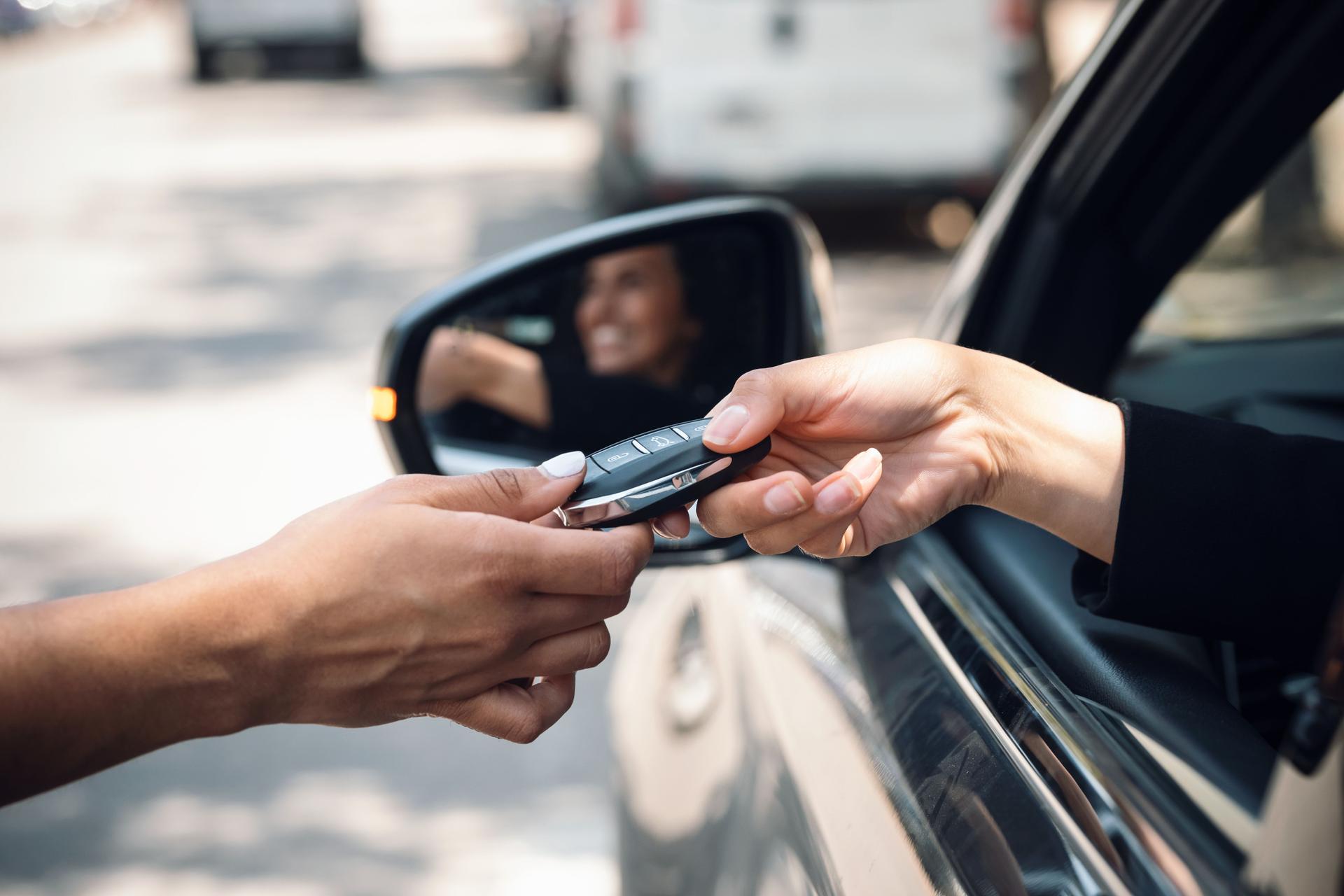 Car rental agency employee giving car keys to beautiful young woman.
